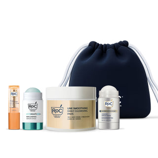 RoC skincare products (Revive + Glow Eye Balm, Hydration+ Serum Stick, Line Smoothing Daily Cleansing Pads, Derm Correxion Firming Serum Stick) with a navy holiday cosmetic bag on a white background