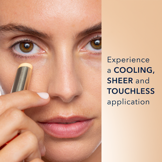 Image of model applying Eye Balm to her undereye area. Experience a cooling sheer and touchless application
