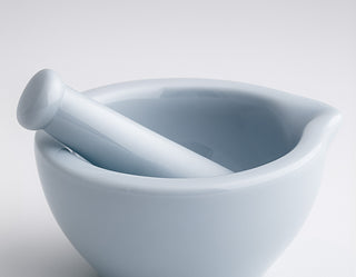 White ceramic mortar and pestle on a light gray background