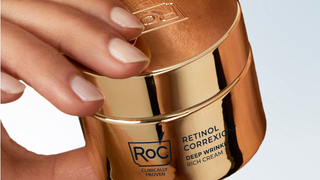 Gold container of Roc Retinol Correxion Deep Wrinkle Rich Cream held by a hand.