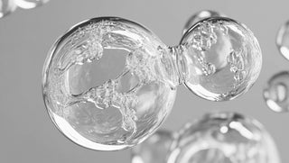 Close-up of a glass model of a water molecule on a gray background