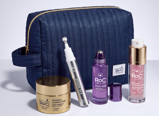 A set of RoC skincare products arranged in front of a navy blue quilted cosmetic bag. The products include a gold jar of Retinol Correxion Deep Wrinkling Retinol Cream, a silver and white Eye Repair pen, a purple bottle of Even Tone serum, and a pink bottle of Retinol Correxion treatment.