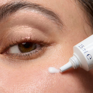 Close-up of a person applying eye cream with a dropper to their under eye.