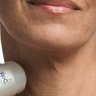Close-up of a person using the derm correxion firming serum stick on their neck.