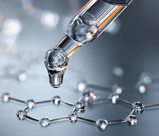 A dropper with a clear liquid above a molecular structure on a gray background