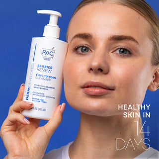 Healthy skin in 14 days. Model holding Barrier Renew® Gel-To-Foam Cleanser bottle next to cheek. 