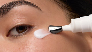 Person applying Derm Correxion Dark Circle Eye Repair Cream to their eye with the metal cooling tip applicator
