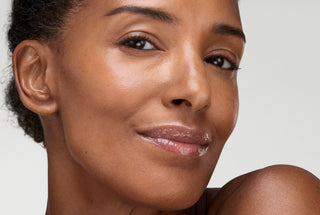 Close-up of a woman's face with RoC Derm Correxion Lip Volumizer on her lips with a neutral background