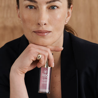 Woman holding a RoC Triple Serum Bottle.
