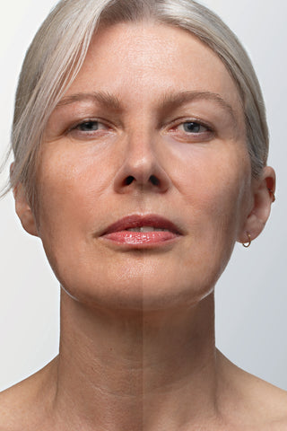 A close-up portrait of a woman with short platinum blonde hair, showing her face and neck against a light gray background.