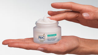 Hands holding a jar of Roc Hydration+ Moisturizers against a white background