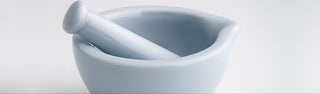 White ceramic mortar and pestle on a light gray background