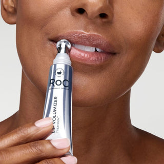 Person using a ROC Lip Volumizer on their lips with a neutral background