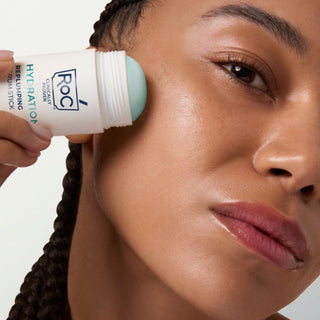 Person applying RoC Hydration+ Serum Stick to their face with a neutral background